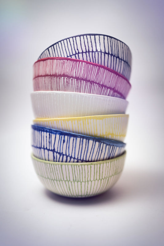 Stack of colorful ceramic bowls with a patterned, drawn design.